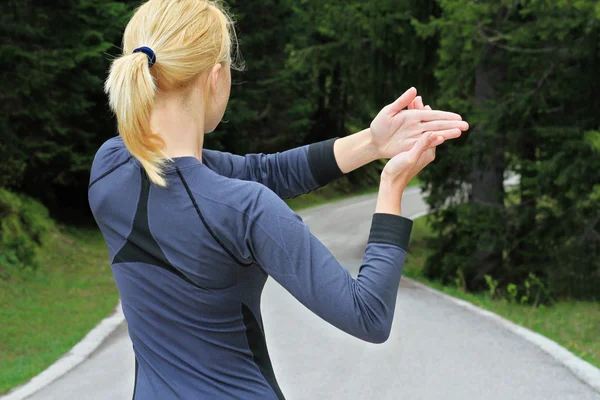 Fitness woman stretching arms before running or cardio workout in beautiful nature forest landscape.