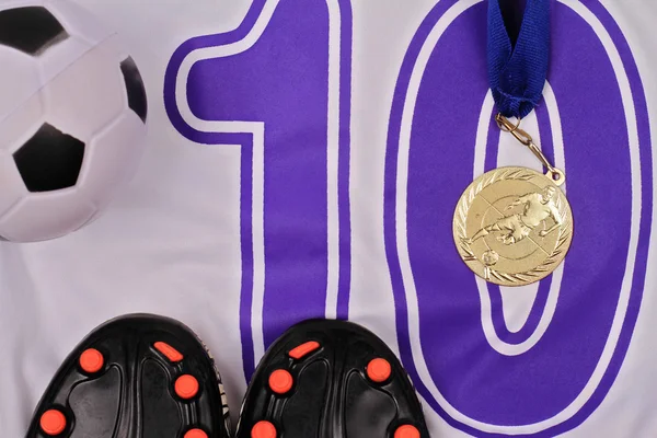 Children football : football boots, ball and uniform and gold medal, flat lay composition. Competition and winning concept