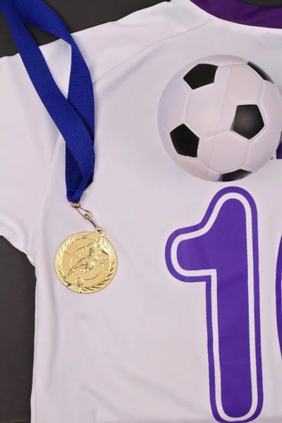 Children football : football boots, ball and uniform and gold medal, flat lay composition. Competition and winning concept