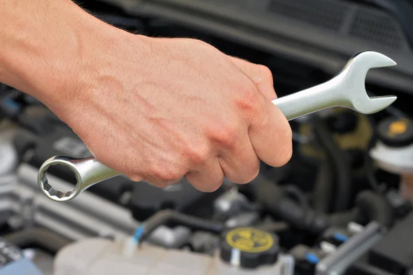 Car service concept, Mechanic Hand Hold Spanner Tool, man checking the condition of car engine.