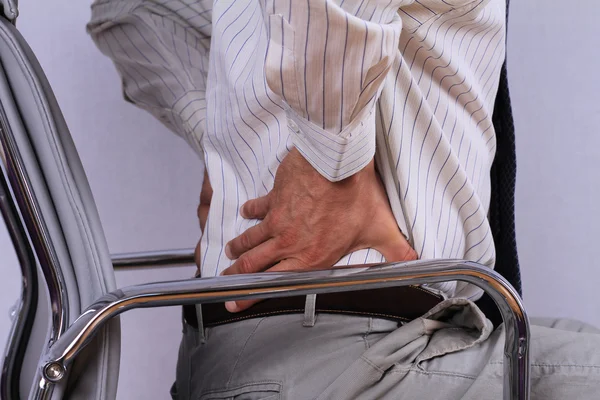 Business man with back pain sitting in an office chair. Pain relief concept