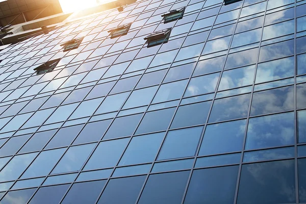 Modern business building windows. Blue Glass Facade with Geometric Lines, Sunlight and Clouds Reflecting