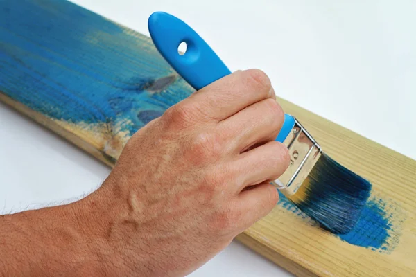 Close up on male hand painting wooden plank, furniture with paitbrush