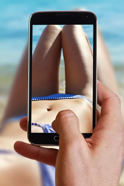 Male hand taking photo of Close up on attractive woman enjoying summer on the beach near sea with cell, mobile phone.