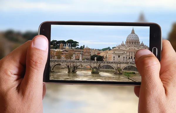 Male hand taking photo of st peter basilica in Vatican and river Tiber from the bridge in Rome with cell, mobile phone. Europe travell, Italian holiday.