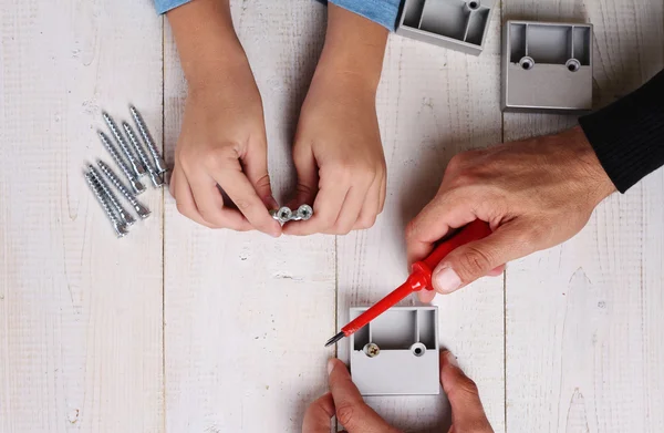 Father and son use Screwdriver. Boy helping his dad with building work at home.  Family concept. DIY toolsBoy helping his dad with building work at home.  Family concept. DIY tools