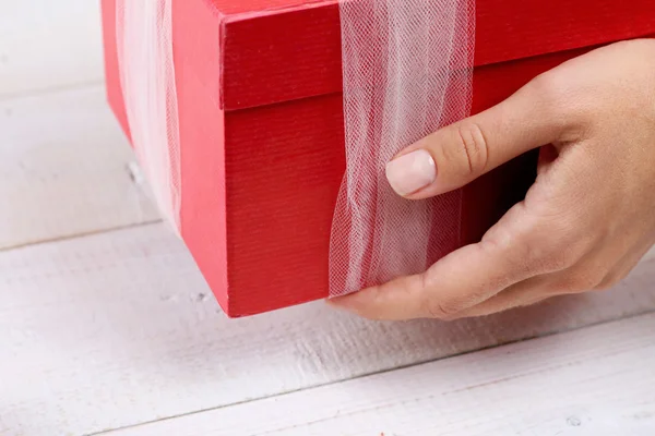 Close up on female hands holding red present with white Ribbon . Gift box packaging. Birthday, New year, Valentine\'s Day, 8 march, Christmas concept.