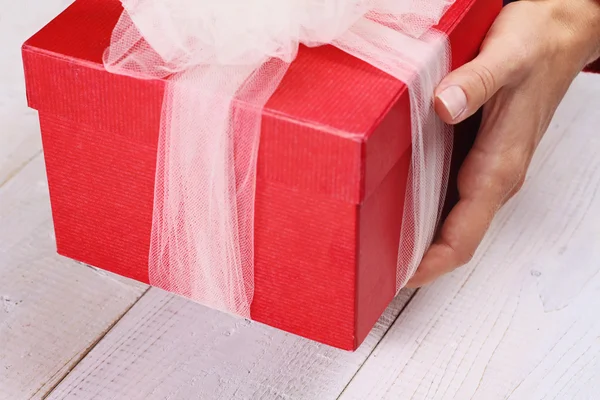 Close up on female hands holding red present with white Ribbon . Gift box packaging. Birthday, New year, Valentine\'s Day, 8 march, Christmas concept.