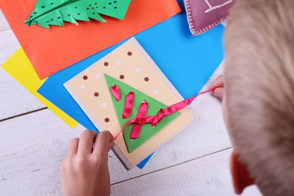 Close up on child making Christmas Tree from colored paper.   Kids Art, Art Projects, Handmade New Year decorations