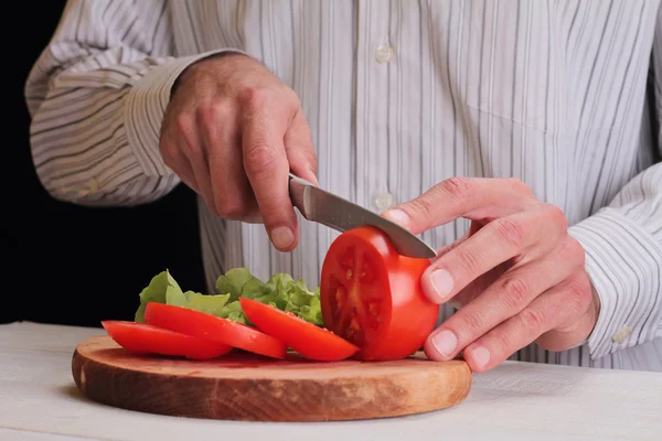 Close up on male hands cutting tomato, making salad. Chief cutting vegetables. Healthy lifestyle, diet food