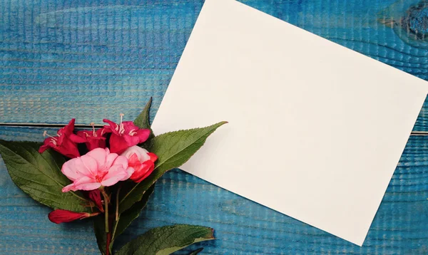 Blank message card and bouquet of flowers on blue wooden rustic table. Love, romantic, concept . Copy space background