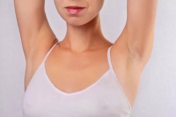 Armpit epilation, lacer hair removal. Young woman holding her arms up and showing underarms, armpit, ideal smooth clear skin
