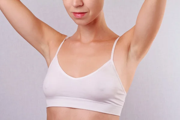 Armpit epilation, lacer hair removal. Young woman holding her arms up and showing underarms, armpit, ideal smooth clear skin