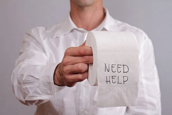 Man holding toilet paper with words need help written on it