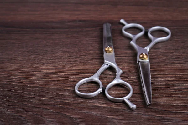 Stylish Professional Barber Scissors, Hair Cutting and Thinning Scissors on wooden background. Hairdresser salon concept. Haircut accessories