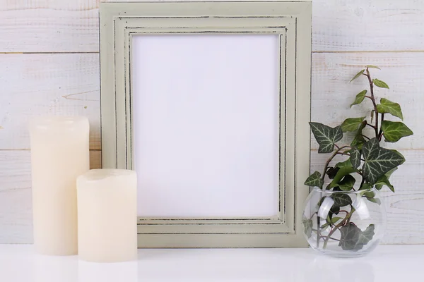 Empty picture frame with copy space blank on white rustic background and Ivy plant.  Scandinavian style home interior decoration
