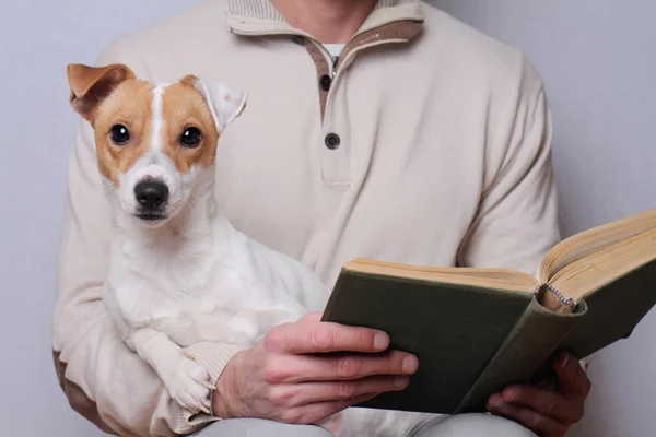 Man reading book and hugging dog