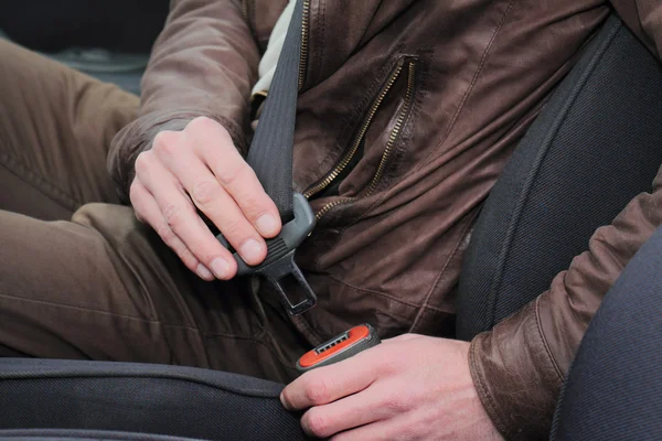 Driving safety concept. Man fastening seat belt in car close up