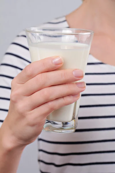 Woman holding a glass of milk close up. Selective focus on glass of milk