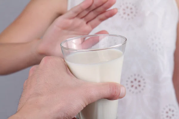 Lactose intolerance. Dairy Intolerant Woman refuses to drink milk. Selective focus on glass of milk