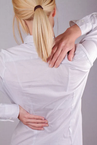 Woman with neck / back pain. Business woman rubbing her painful back close up. Pain relief concept