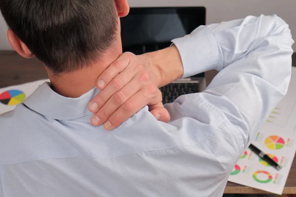 Man with back pain. Business man rubbing his painful neck close up
