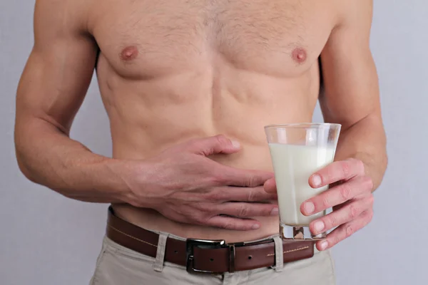 Man with stomach pain holding a glass of milk. Dairy Intolerant person. Lactose intolerance, health care concept.
