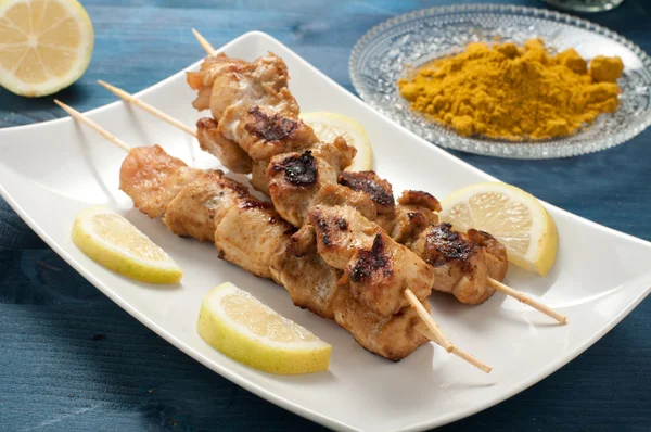 Indonesian chicken satay skewers with curry , peanut butter and soy sauce