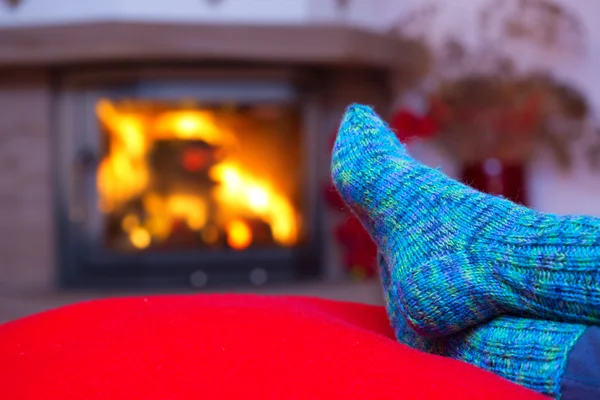 Feet in woollen blue socks by the fireplace.