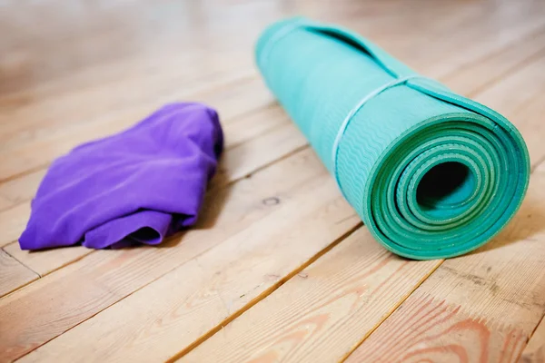 Mat for yoga rolled-up on wooden floor