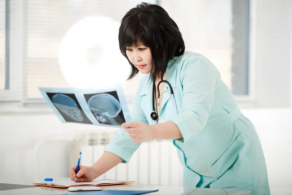 Young female Asian doctor looking at the x-ray picture
