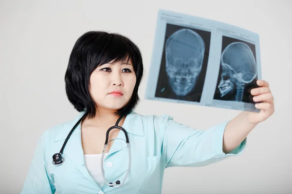 Young female Asian doctor with stethoscope looking at the x-ray