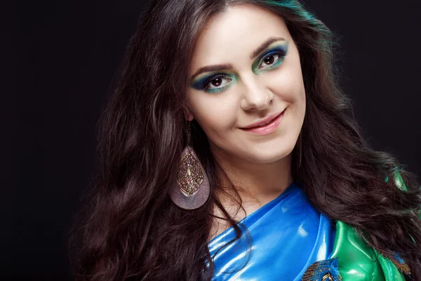 Beauty closeup portrait of a beautiful girl, blue green sari with peafowl feathers in the dress design. Artistic makeup, attractive, mysterious lady, peacock earrings.