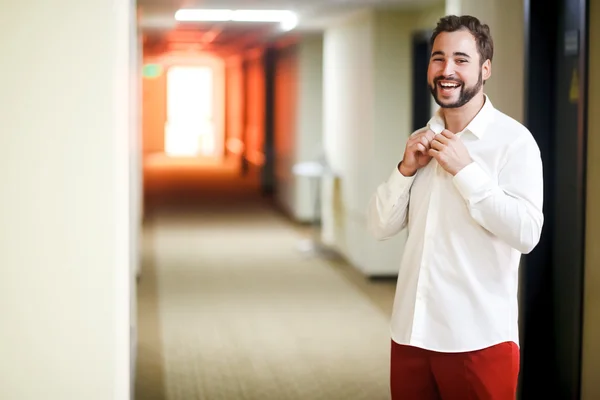 Handsome cheerful groom laughs in hallway of the hotel