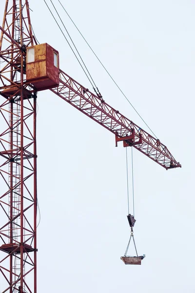 Tower crane carries load in bucket gas cylinders for cutting and welding.