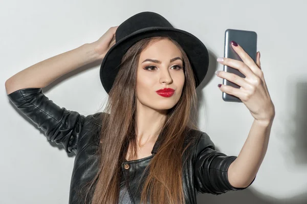 Beautiful young woman photographing herself on telephone