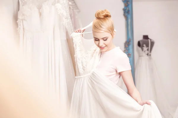 Cheerful future bride is choosing her attire