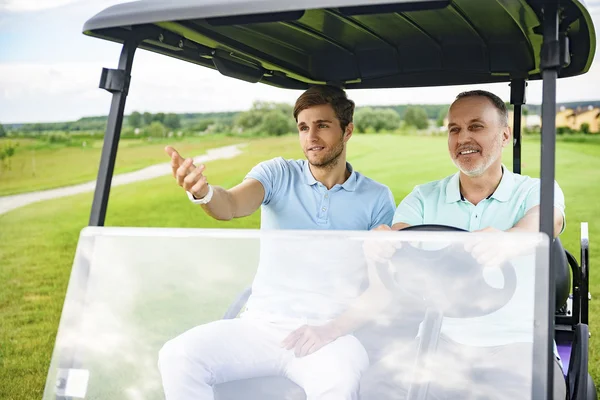 Two men driving cart on golf course