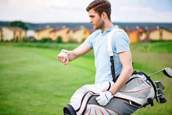 Young golfer checking time on smartwatch