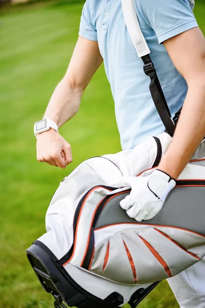 Young golfer checking time on smartwatch