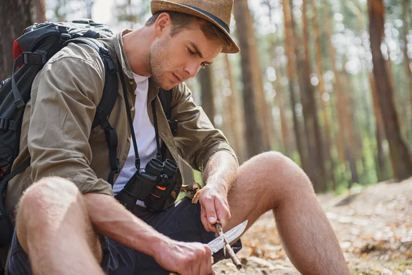 Skillful man whittling pole in forest