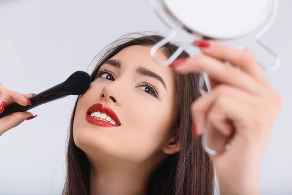 Joyful young woman doing make-up