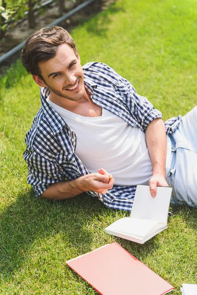 Cheerful male student relaxing on lawn