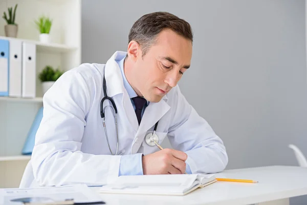 Portrait of adult doctor sitting at his desk