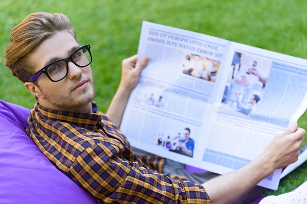 Carefree guy reading paper outdoors