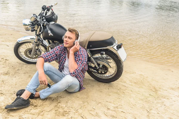 Young guy sitting next to his vintage motorcycle