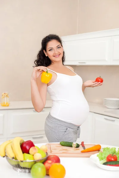 Beautiful young expectant mother is cooking in kitchen