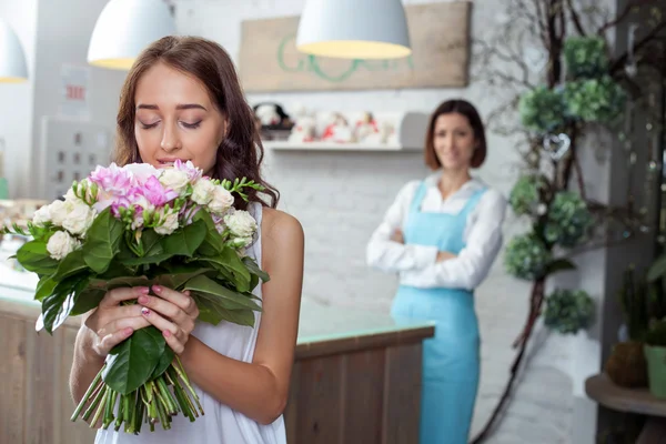 Attractive young woman is buying flowers in store