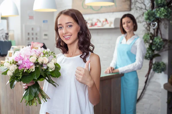 Beautiful young woman likes flowers in store