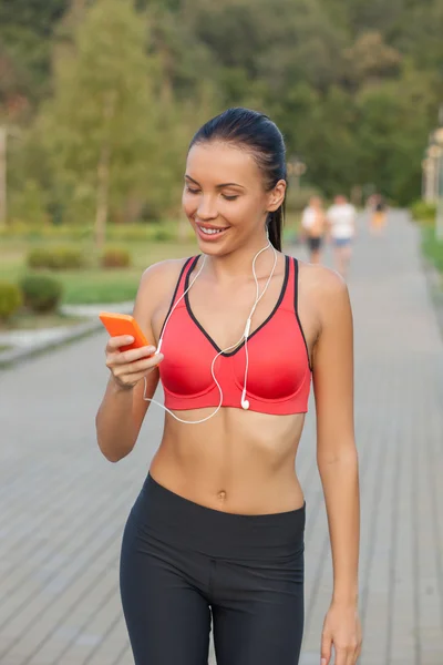 Beautiful healthy female runner is using telephone